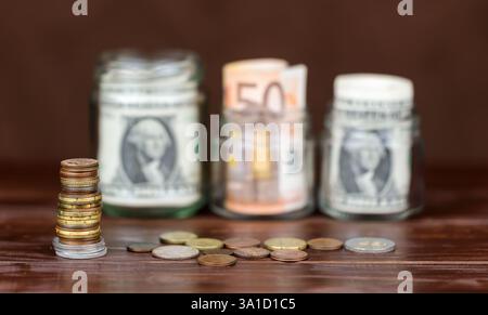 Banconote in euro e banconote in dollari USA in vasetti con monete. Sfondo del tasso di cambio delle valute. Foto Stock