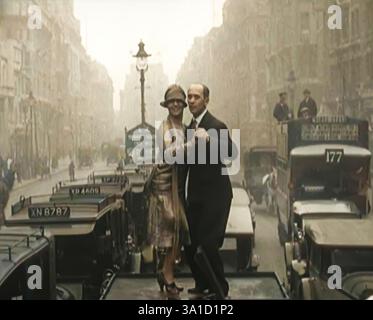Una coppia che danzava il Charleston sulla cima di un'auto che percorreva una London Street, 1926. Da "Time to Remember 1926 - Short Sharp Shower" ( Reel 4); documentario sul 1926 - General Strike, International Politics, Dancing, Weather and record feats. (Fermo bianco e nero colorato) Foto Stock