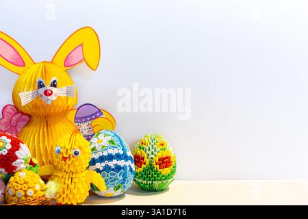 Sfondo pasquale e decorazioni per la casa con uova di Pasqua origami colorate, coniglietto e chics, ornamenti floreali e decorazioni di carta nella corna Foto Stock