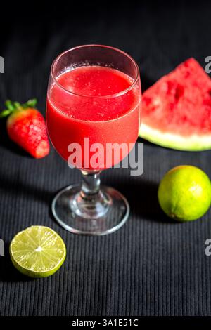 Bicchiere di succo di fragola con limone su sfondo scuro. Foto Stock