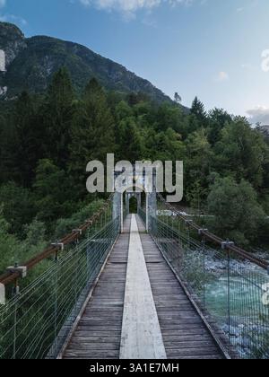 Un ponte di legno attraversa un fiume, con una montagna sullo sfondo. Il ponte è vecchio e ha un'atmosfera rustica. Gli alberi e le montagne circostanti c Foto Stock