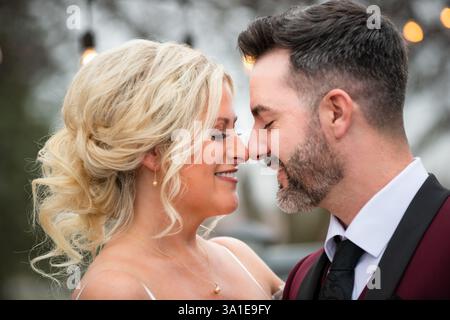 La sposa e lo sposo condividono un bacio tenero il giorno del loro matrimonio, primo piano. Amore e romanticismo catturati in un momento emozionante. Foto Stock