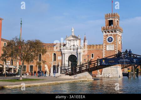 Venezia, Italia - 12 ottobre 2024: L'ingresso storico dell'Arsenale di Venezia con la sua porta in marmo ornato, la torre dell'orologio e il ponte in legno Foto Stock