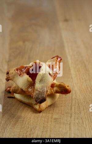 Tre pasticcini con marmellata l'uno sopra l'altro. I dolci sono impilati uno sopra l'altro su un tavolo di legno. hamantash Foto Stock