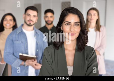 Giovani membri del team multietnici che si pongono in casa, si concentrano sul capo femminile Foto Stock