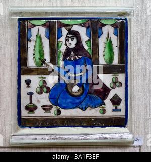 Piastrelle in ceramica persiana in stile Qajar raffiguranti una donna con un setar, fotografata in un negozio di arte decorativa a Delhi, India. Foto Stock