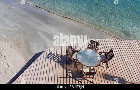 Tavolo e quattro sedie che lo circondano su un pavimento di legno vicino alla riva del mare in Egitto Foto Stock