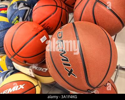 Bobruisk, Bielorussia - 22 febbraio 2025: Palline da basket e pallavolo dai colori vivaci riempiono il rack, mostrando vari design e texture. Foto Stock