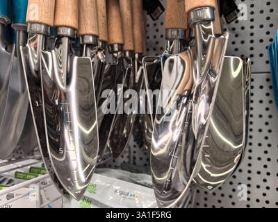 Bobruisk, Bielorussia - 22 febbraio 2025: Le frattazzatrici da giardino in metallo lucido con manici in legno sono disposte in modo ordinato. Foto Stock