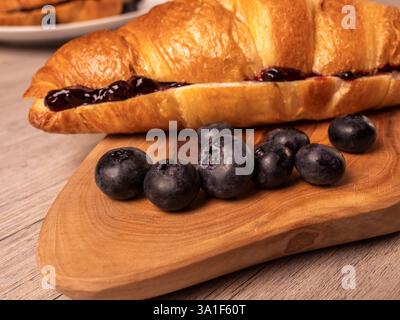 Primo piano di croissant ripieni di marmellata e mirtilli freschi sul tagliere Foto Stock