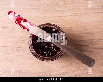 Coltello su un vasetto di marmellata di mirtilli. Vista dall'alto. Foto Stock