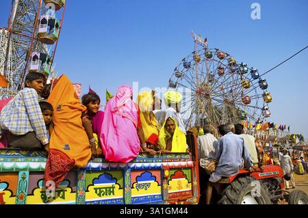 Un gruppo di abitanti del villaggio in abiti colorati arriva a bordo di un trattore all'annuale fiera del bestiame di Pushkar, Pushkar, Rajasthan, India, Asia Foto Stock