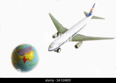 Aeroplano giocattolo Boeing 777 e globo su sfondo bianco Foto Stock