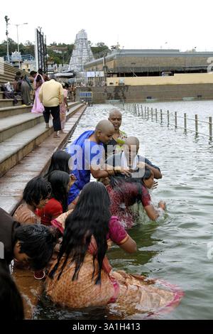Devoti che bagnano la vasca sacra (Pushkarini) a Tirumalai, Tirupati, Andhra Pradesh, India, Asia Foto Stock