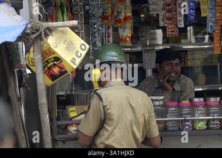 Un agente di polizia fa una telefonata locale da un negozio a Bombay ora Mumbai, Maharashtra, India, Asia Foto Stock