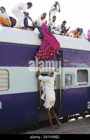 Vecchio che aiuta una donna che cerca di salire sul tetto del treno alla stazione ferroviaria di Jodhpur, Rajasthan, India, Asia Foto Stock
