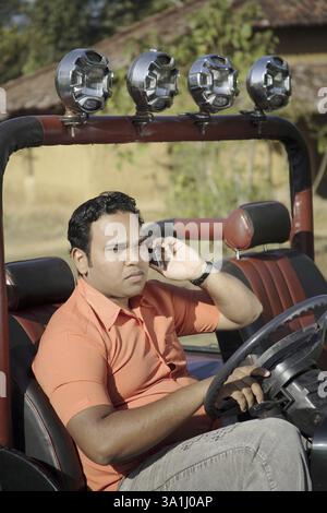 Giovane indiano del sud asiatico seduto al posto di guida in jeep indiana e tenendo il volante, India MR# 703H Foto Stock