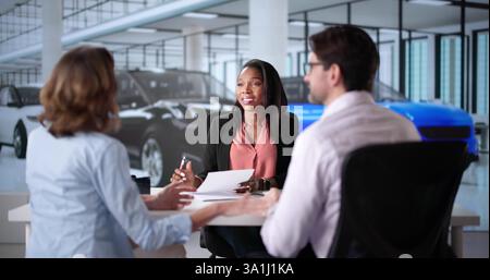 Coppia felice di negoziare un contratto auto con diversi agenti di vendita della concessionaria. Foto Stock