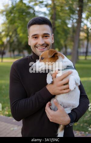 Un giovane ama trascorrere momenti felici all'aperto, tenendo vicino il suo cane giocoso mentre è circondato dalla bellezza della natura. I loro sorrisi riflettono un legame di frie Foto Stock