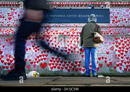 Foto datata 13/01/22 di una donna in pausa per guardare le dedicazioni scritte sul National Covid Memorial Wall a Westminster, Londra. A cinque anni dal primo confinamento della Covid-19 non sono migliorate le esperienze di salute e solitudine delle persone, le cifre suggeriscono, con un'attenzione benefica che gli effetti "duraturi" della pandemia continuano a lasciare "molte persone isolate”. Data di pubblicazione: Domenica 9 marzo 2025. Foto Stock