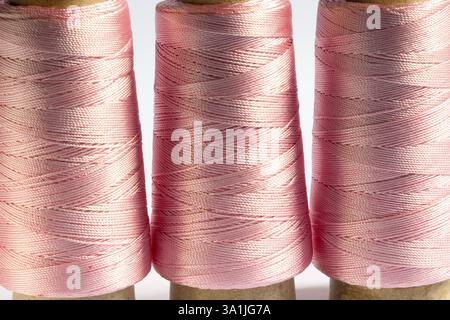 Concept, tre forme cilindriche a uncinetto rosa lucido setoso filo di colore su sfondo bianco Foto Stock