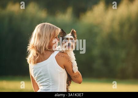 Vista posteriore. La bella donna è con il suo carino cane all'aperto sul campo. Foto Stock