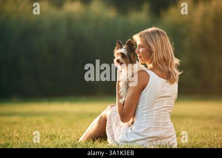 Vista posteriore. La bella donna è con il suo carino cane all'aperto sul campo. Foto Stock