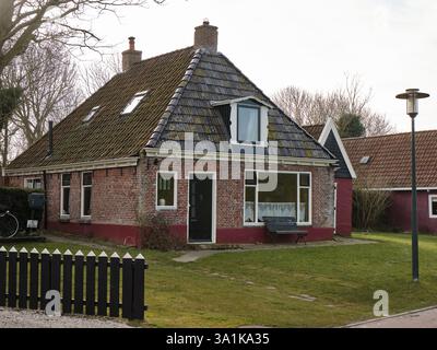 6 marzo 2025 - Moddergat-Paesi Bassi: Tradizionale casa dei pescatori olandesi con pareti in mattoni rossi e tetto piastrellato nello storico villaggio di pescatori Frisia. Foto Stock