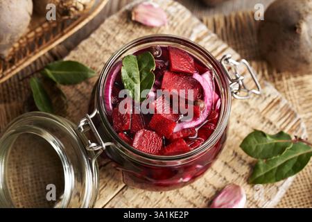 Preparazione di barbabietole fermentate in un vaso di vetro con barbabietola fresca, cipolle, aglio e spezie Foto Stock