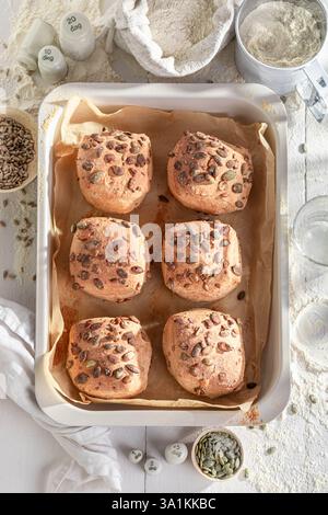 Panini di semi di zucca preparati al momento accompagnati da prodotti essenziali da forno. Una genuina esperienza di pasticceria. Foto Stock