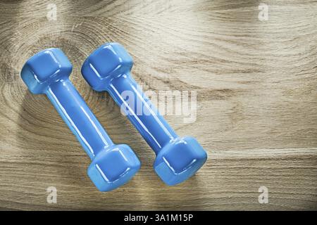 Un paio di pesi a manubrio blu su una tavola di legno Foto Stock