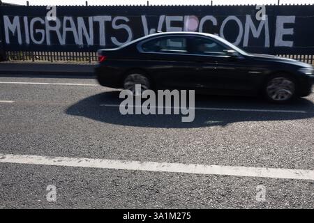 Belfast, Regno Unito. 9 marzo 2025. 09/03/2025 Belfast politica: Migranti benvenuto dipinto su accumulazione a West Belfast credito: Bonzo/Alamy Live News Foto Stock