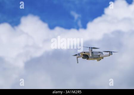 Drone bianco che vola in alto sopra l'isola di siargao, filippine, catturando riprese aeree di un bellissimo cielo nuvoloso durante le vacanze estive Foto Stock