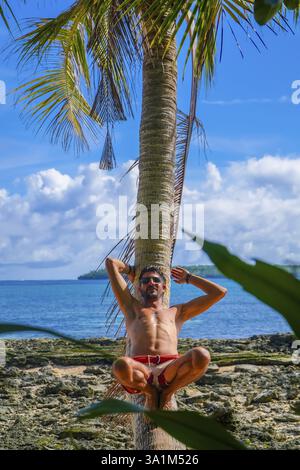 Turista che si rilassa su una palma in una spiaggia tropicale nell'isola di daku, siargao, filippine, godendo delle vacanze estive Foto Stock