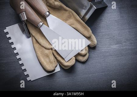 Stucco picchiettio vernice raschietti angolari guanti da lavoro pannello di legno Foto Stock