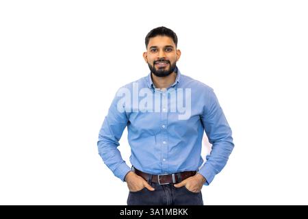 Un giovane imprenditore sicuro di sé con la barba sorride, indossa una camicia blu e un paio di jeans, che irradia successo e fascino accessibile. Foto Stock