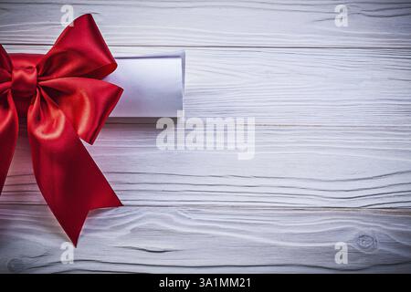 Rotolo di carta con arco rosso su tavola in legno Foto Stock