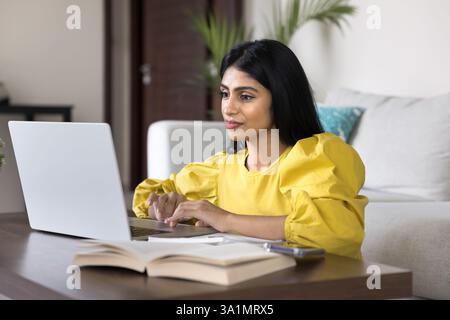 Donna indiana che studia, ricerca o fa lavoro professionale utilizzando un computer portatile Foto Stock