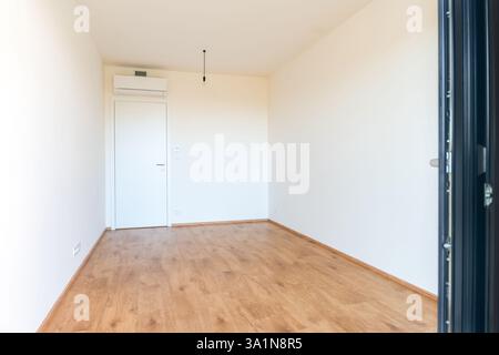 Camera vuota minimalista con aria condizionata e pavimento in legno in un appartamento moderno Foto Stock