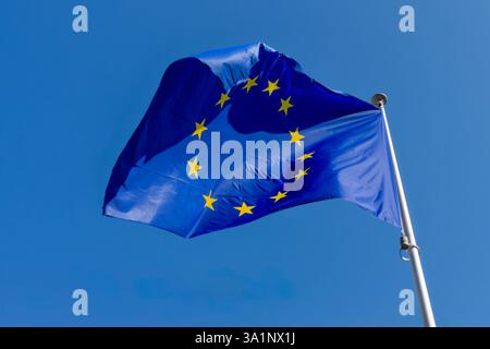 Bandiera europea, simbolo dell'Unione europea (UE), che fluttua contro un cielo blu a Bruxelles, Belgio Foto Stock