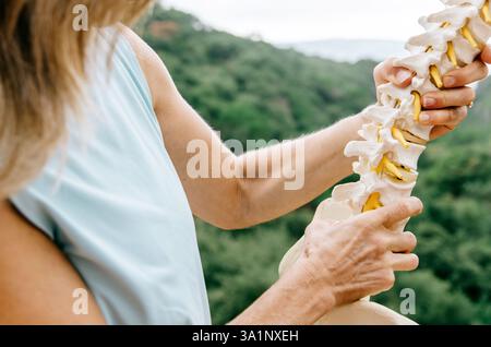 Primo piano del fisioterapista che tiene in mano il modello anatomico della colonna vertebrale Foto Stock