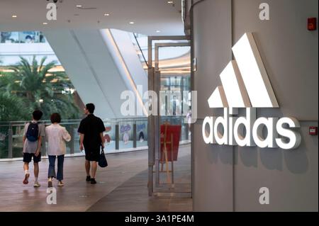 Gli amanti dello shopping passeranno davanti al negozio Adidas, un marchio multinazionale di abbigliamento sportivo tedesco, in un centro commerciale a Shenzhen, in Cina. Foto Stock
