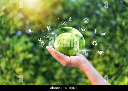 Uomo d'affari con un globo in erba verde con icone ecologiche che simboleggiano la sostenibilità. Perfetto per la responsabilità aziendale, le energie rinnovabili Foto Stock