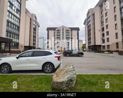 Vista di un edificio a più piani sul cortile con parco giochi e parcheggio per auto e altre case Foto Stock