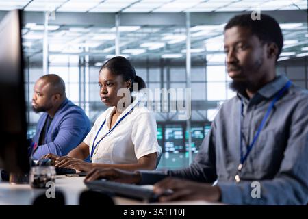 Team di programmatori del data center che esegue test diagnostici di sistema sul computer per risolvere i problemi. I dipendenti che collaborano implementano e controllano gli errori delle utility sul PC per risolvere i problemi di prestazioni della rete Foto Stock