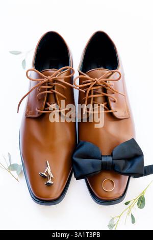 Scarpe con abito marrone con un papillon nero, gemelli e anello nuziale. Foto Stock