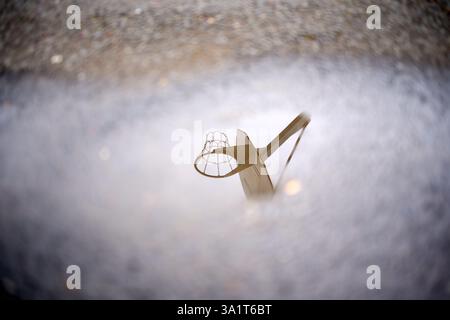 Canestro da basket che si riflette in una pozzanghera dopo la pioggia Foto Stock