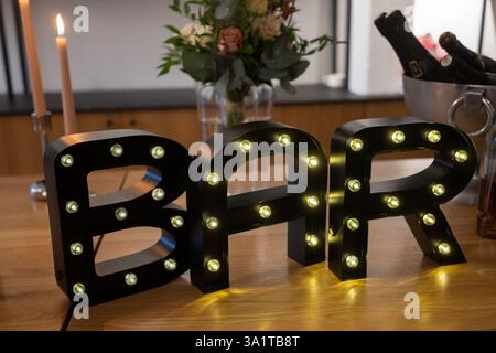 Lettere nere B, A e R con luci a LED sul tavolo in legno. LA BARRA a LED illumina le lettere. Foto Stock