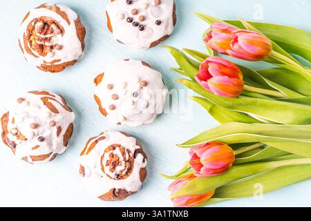 Cupcake o muffin con glassa e tulipani su sfondo azzurro. Torte di Pasqua con gocce di cioccolato. Vista dall'alto. Posizione piatta. Foto di alta qualità Foto Stock
