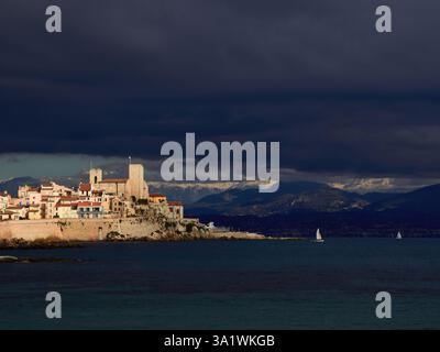 La maestosa città costiera di Antibes sotto i cieli nuvolosi e lo sfondo delle montagne Foto Stock